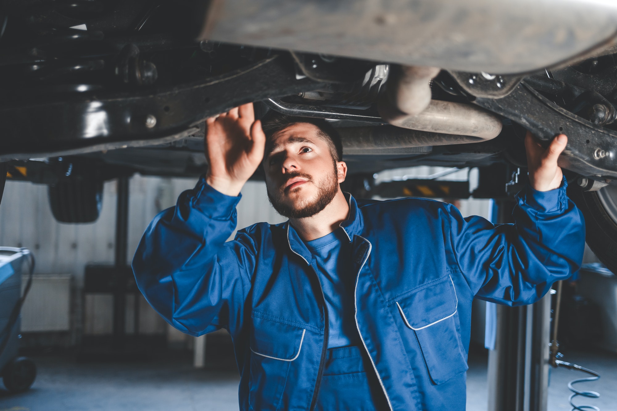 Mechanic inspecting the underside and suspension of a car on a lift